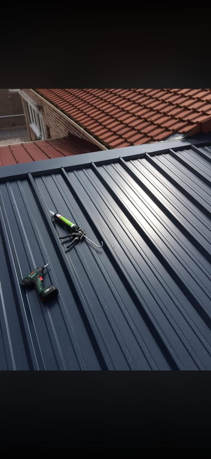 Toiture bac acier anthracite posée par MG Toiture, perceuse et pistolet à mastic sur la couverture neuve