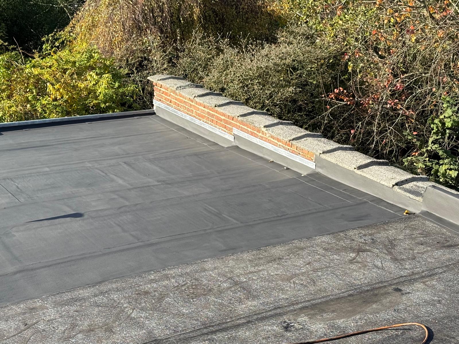 Toiture plate étanchée en EPDM noir avec mur brique